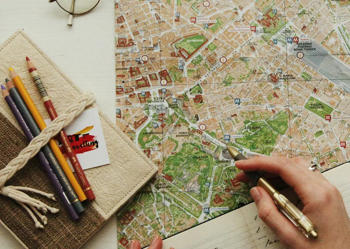 Hands with a pen over a city map with glasses and pencils beside it