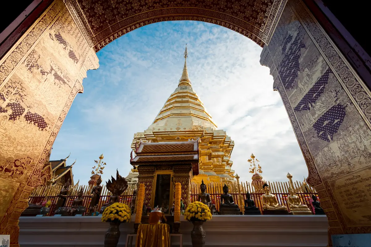 Golden chedi framed by a temple archway under a blue sky