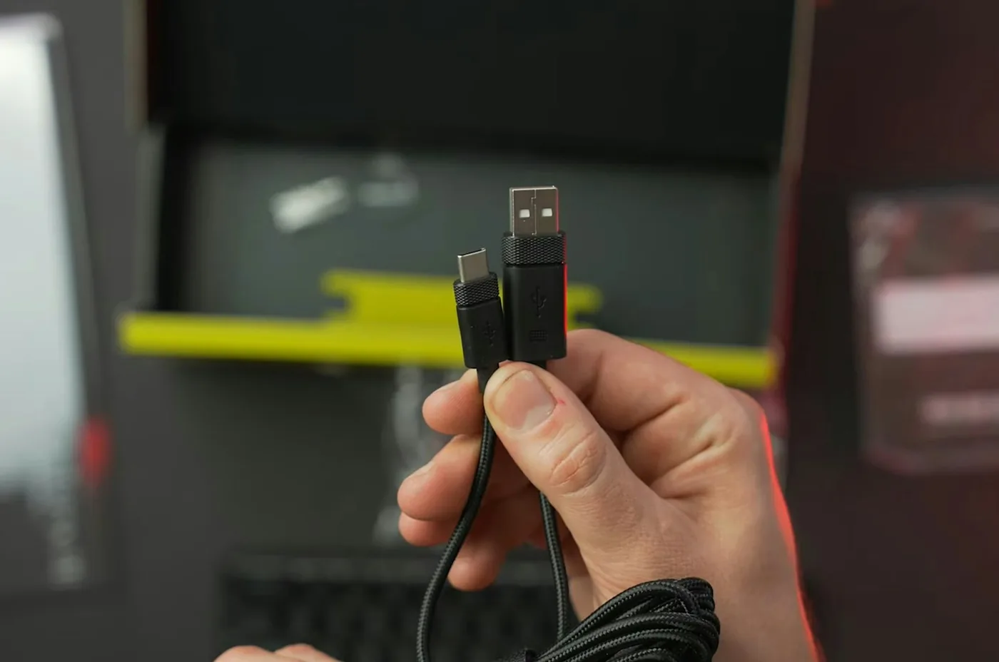 Hand hält ein schwarzes Kabel mit einem USB-C-Stecker und einem USB-A-Stecker