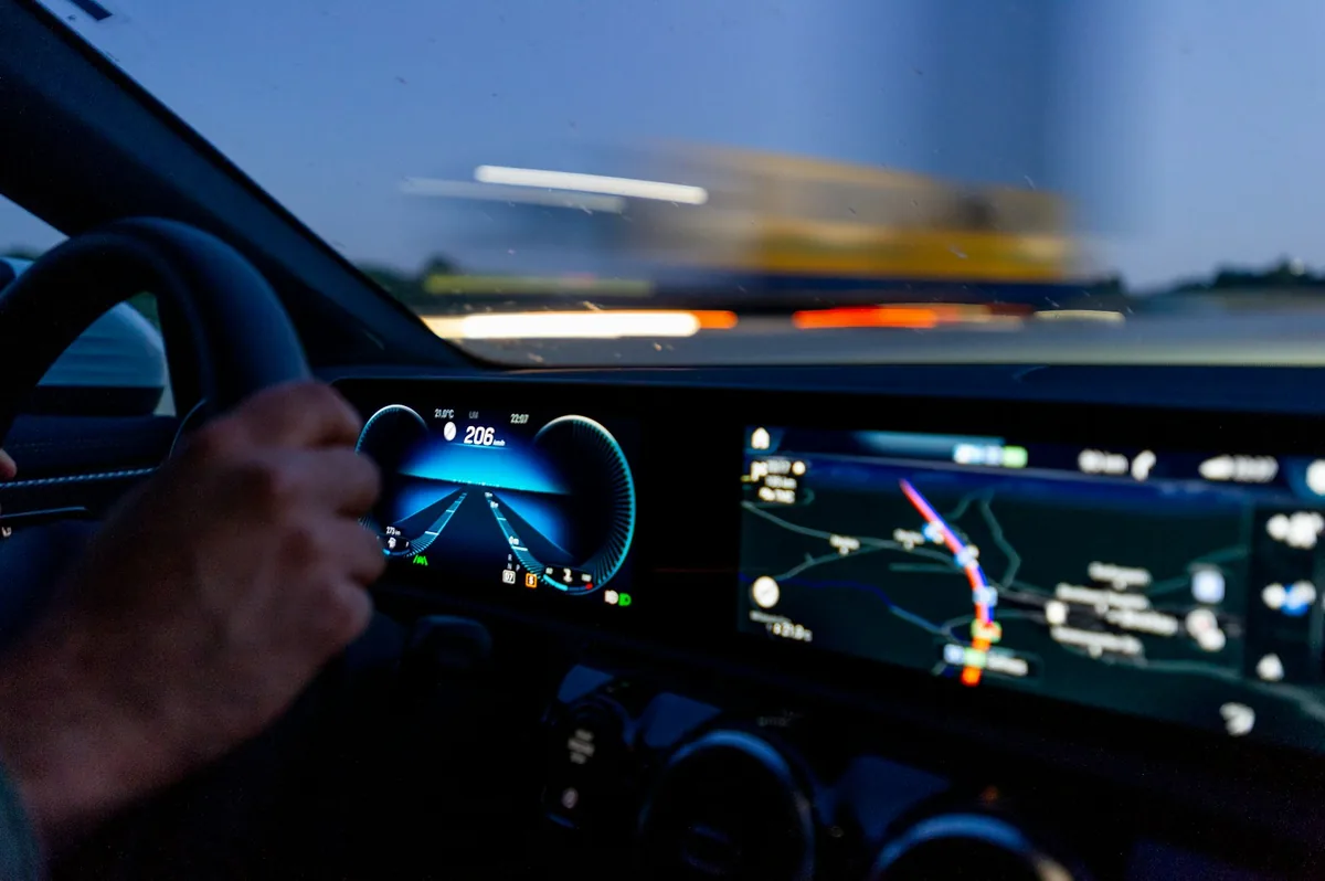 Hand on the steering wheel with a glowing navigation map on the dashboard