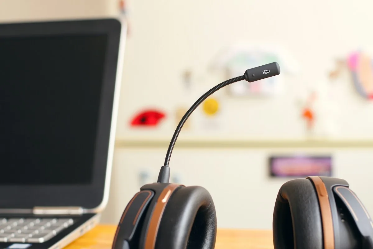Headset with a boom microphone beside a laptop for remote meetings across time zones