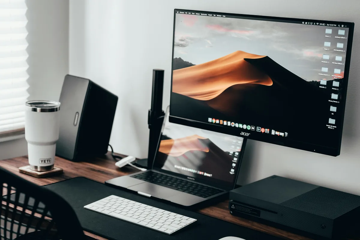 Home office desk with a monitor on an arm and a laptop below it, a second-screen setup