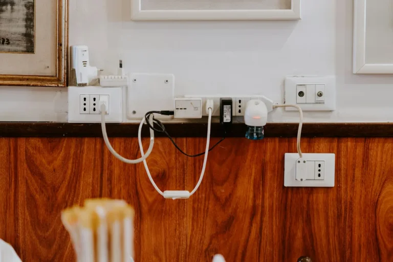 Several wall outlets with cables on a wall above a wooden counter