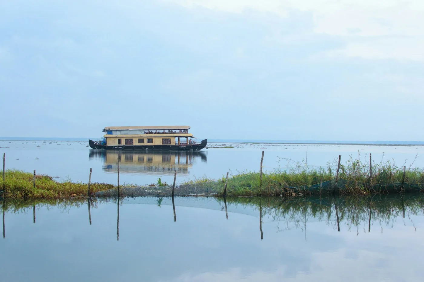 Ein Hausboot treibt allein auf einem ruhigen See unter einem blassen Himmel