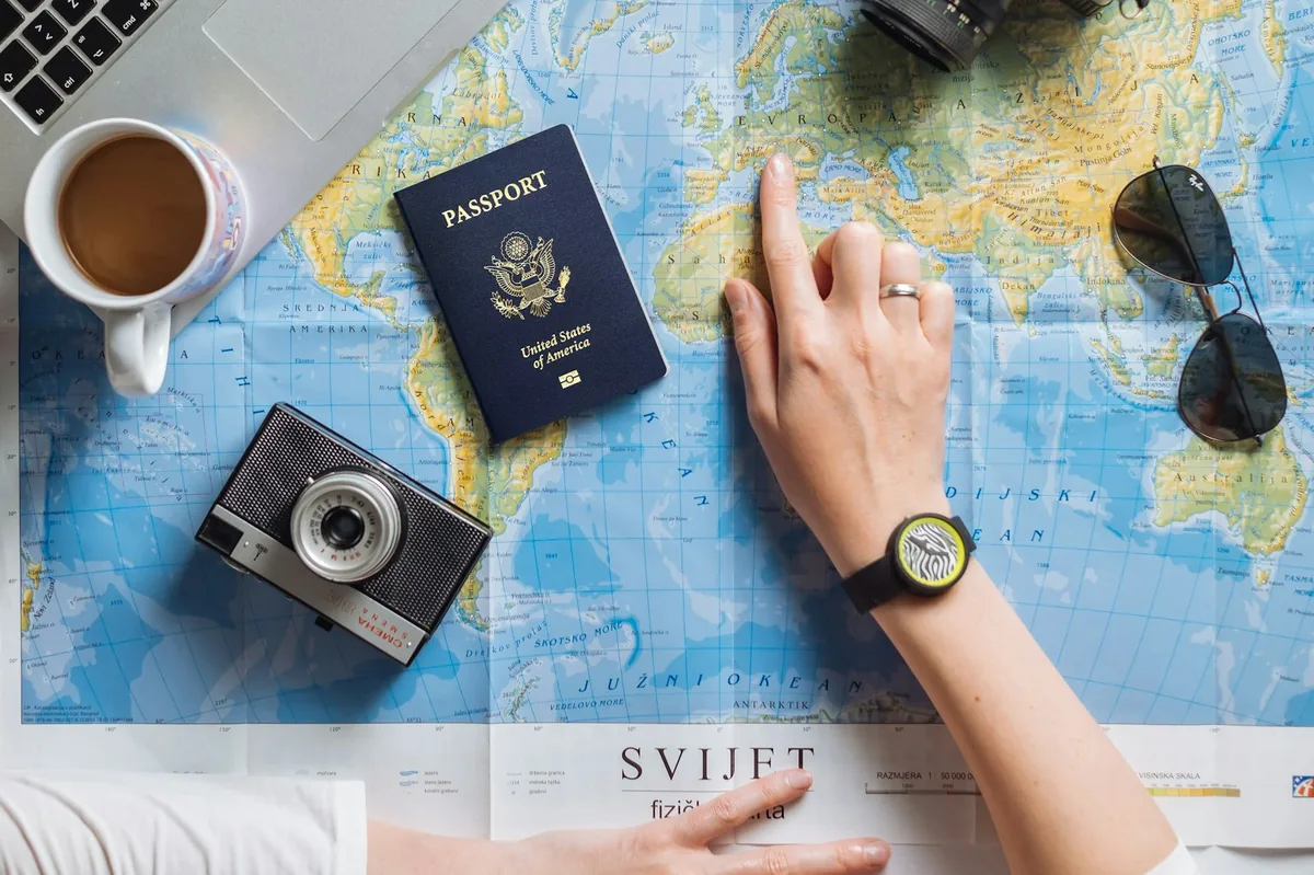 Passport, camera and laptop on a world map while planning, getting an international driving permit before you travel