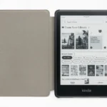 Kindle Paperwhite mostrando su pantalla de inicio junto a una funda gris abierta