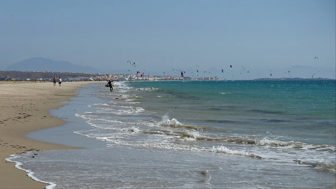 Waves on the shore at Tarifa with many kites flying in the distance