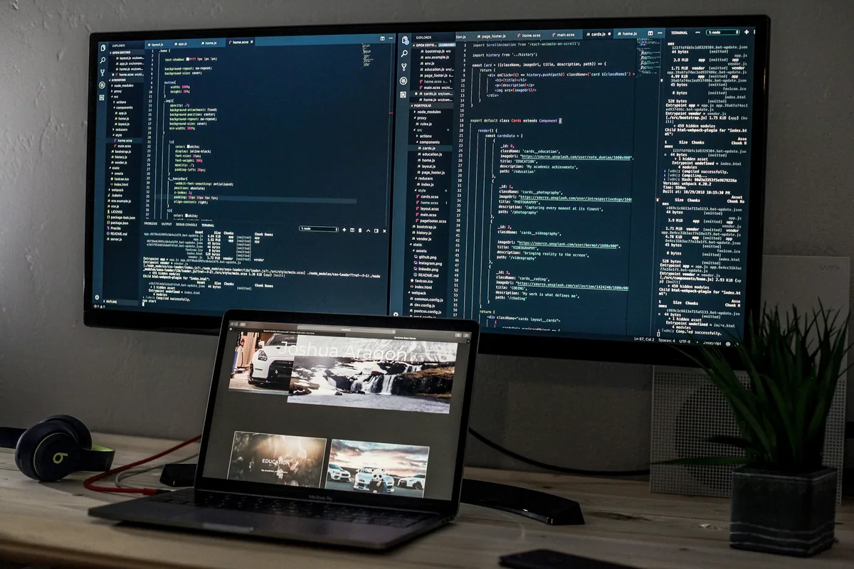 Laptop on a desk in front of a wide external monitor, the second screen a portable monitor gives you on the road