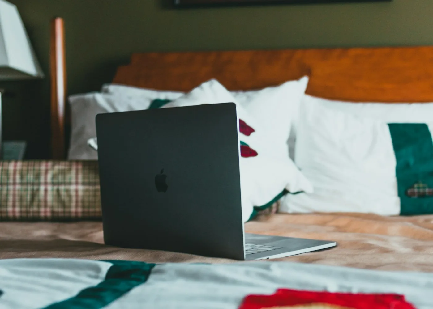 Laptop open on a hotel bed in front of pillows