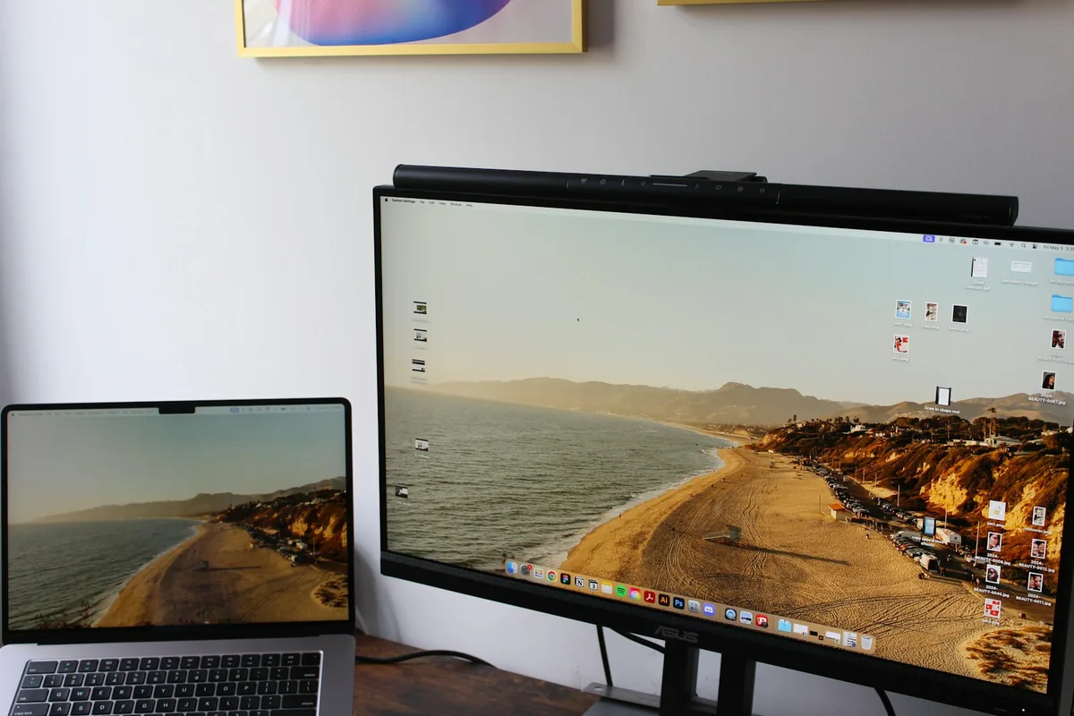 Laptop next to a second screen on a white desk