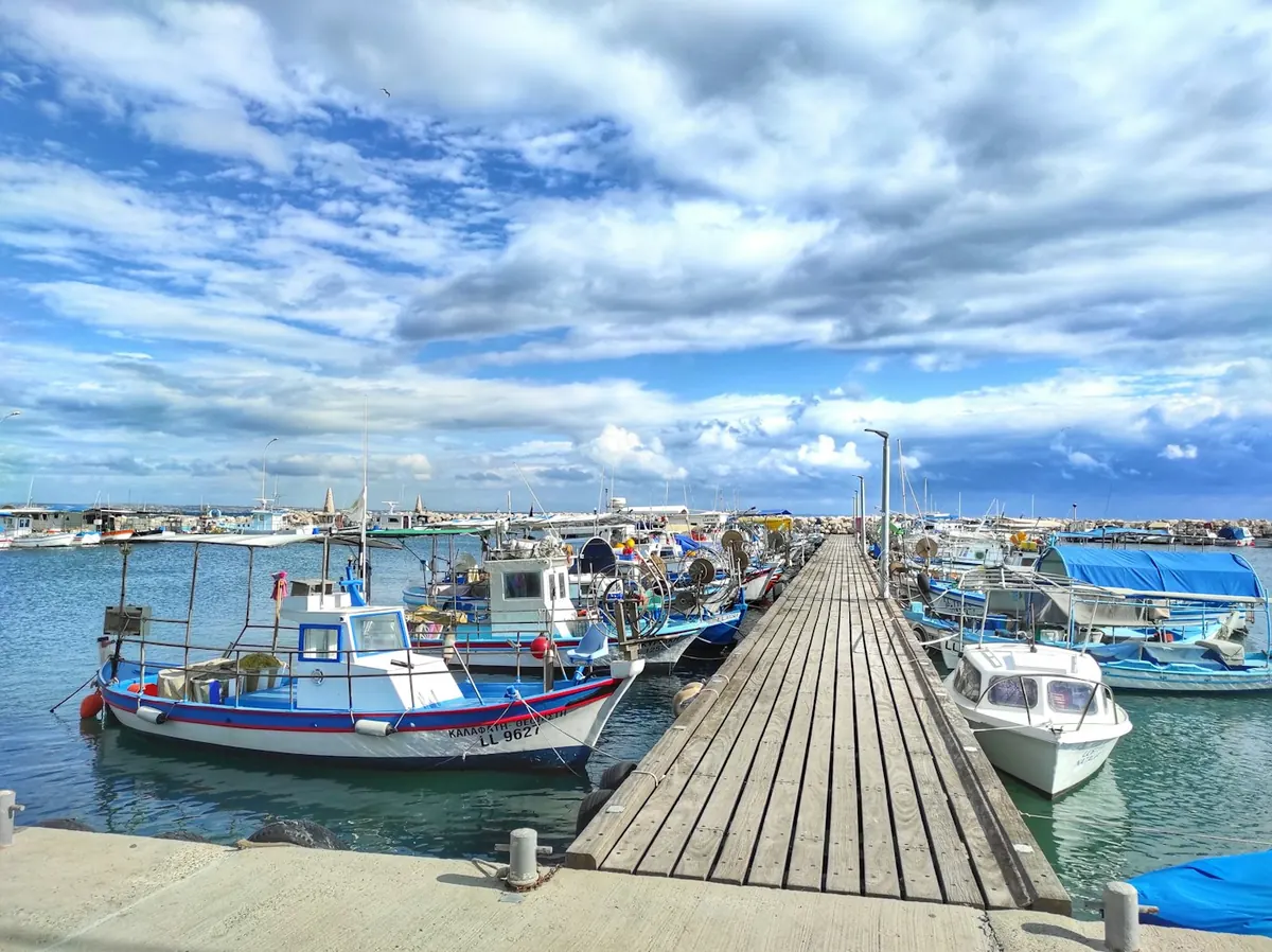 Small boats docked along a wooden pier in the marina of Larnaca, Cyprus