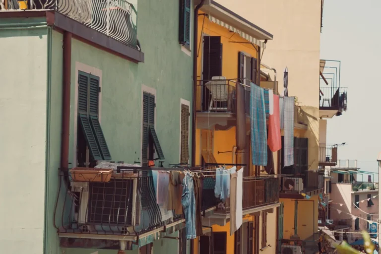 Laundry hanging from balconies on colourful houses in a coastal town