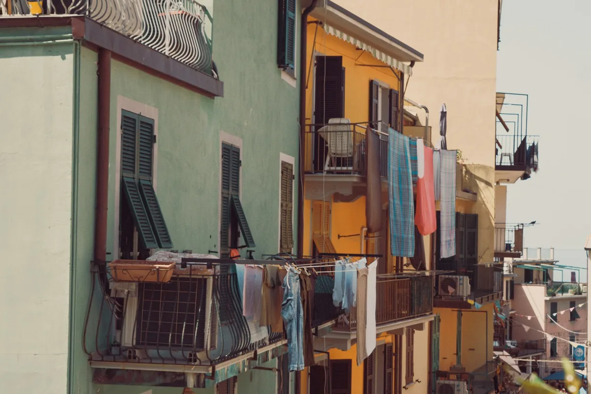 Laundry hanging from balconies on colourful houses in a coastal town