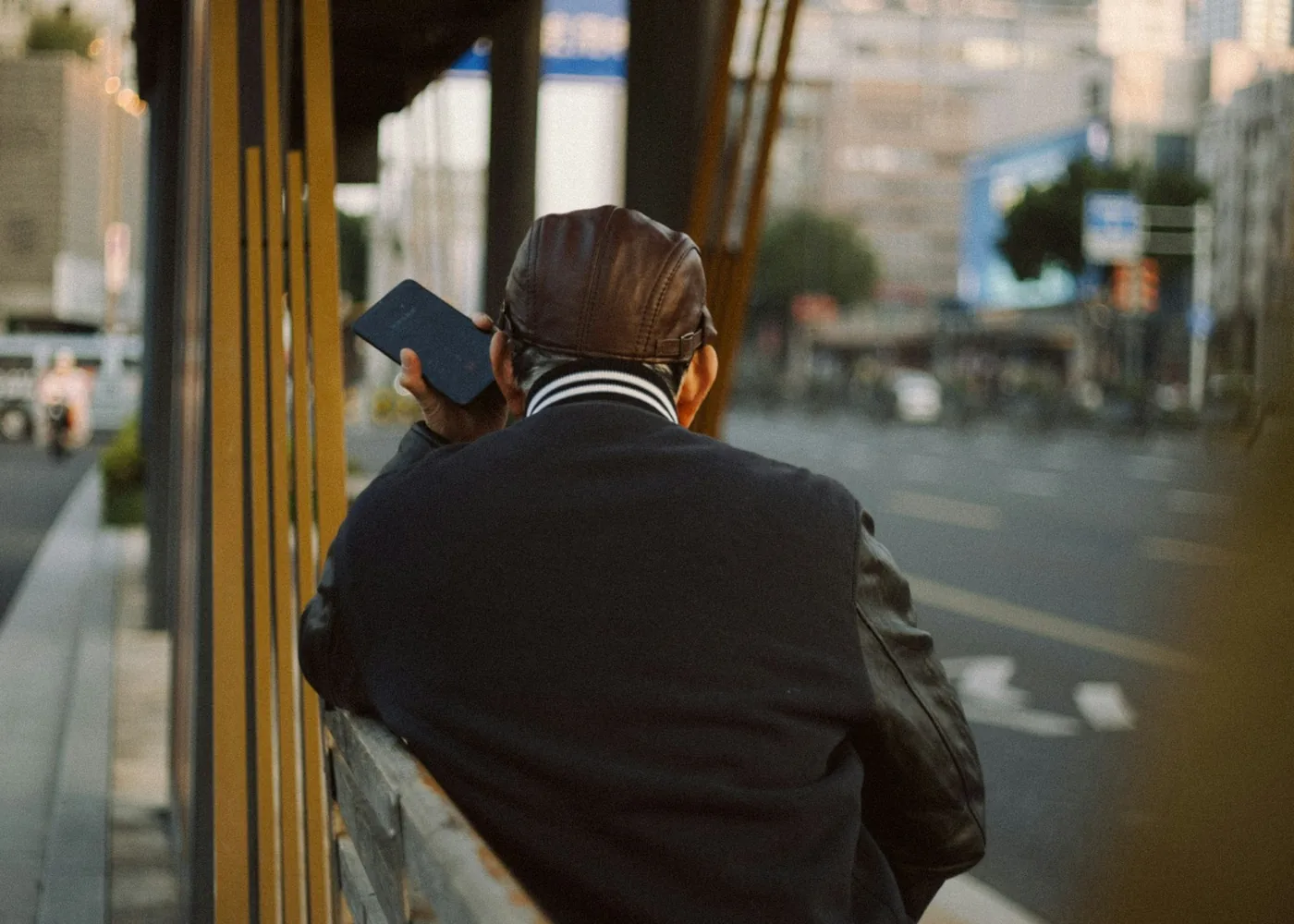 Man looking at his phone while sitting at a city bus stop