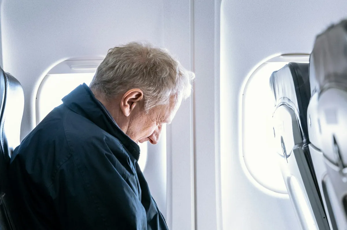 Man reading a book in an airplane window seat