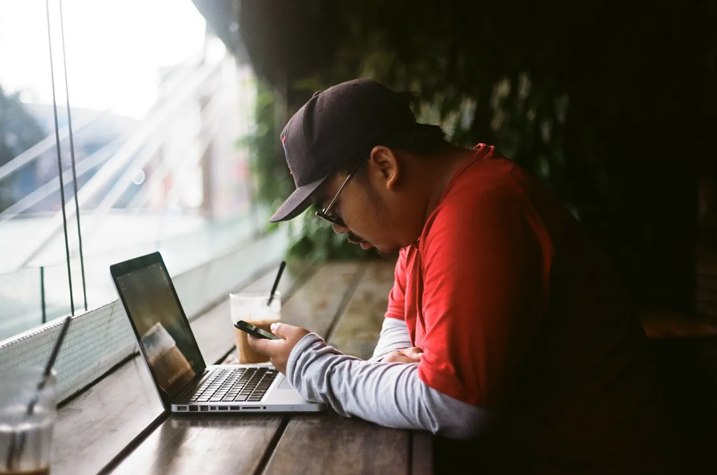 Man sitting with a laptop at a table, choosing which portable monitor to pack for a day of work