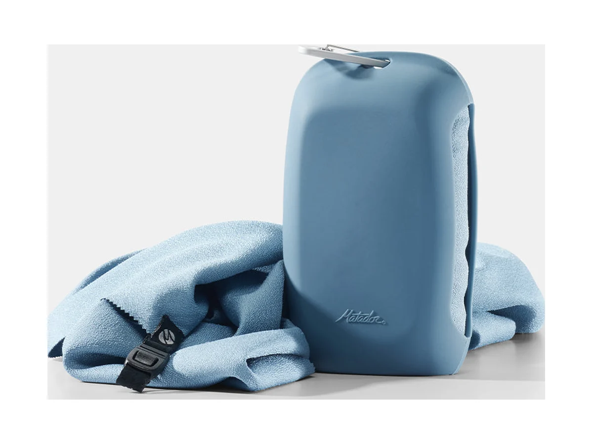 Matador NanoDry packable shower towel in blue next to its silicone case