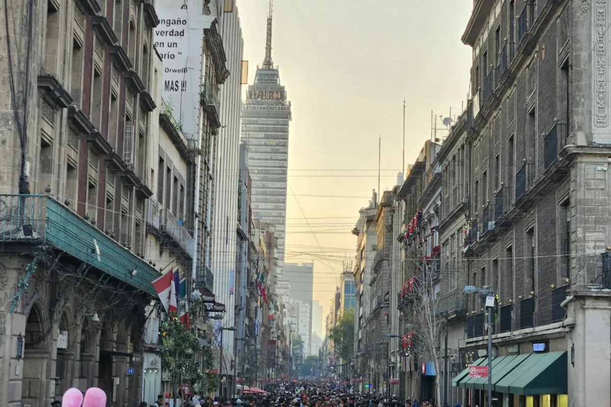 Menschenmassen laufen eine belebte Straße zwischen hohen Gebäuden im Zentrum von Mexico City entlang