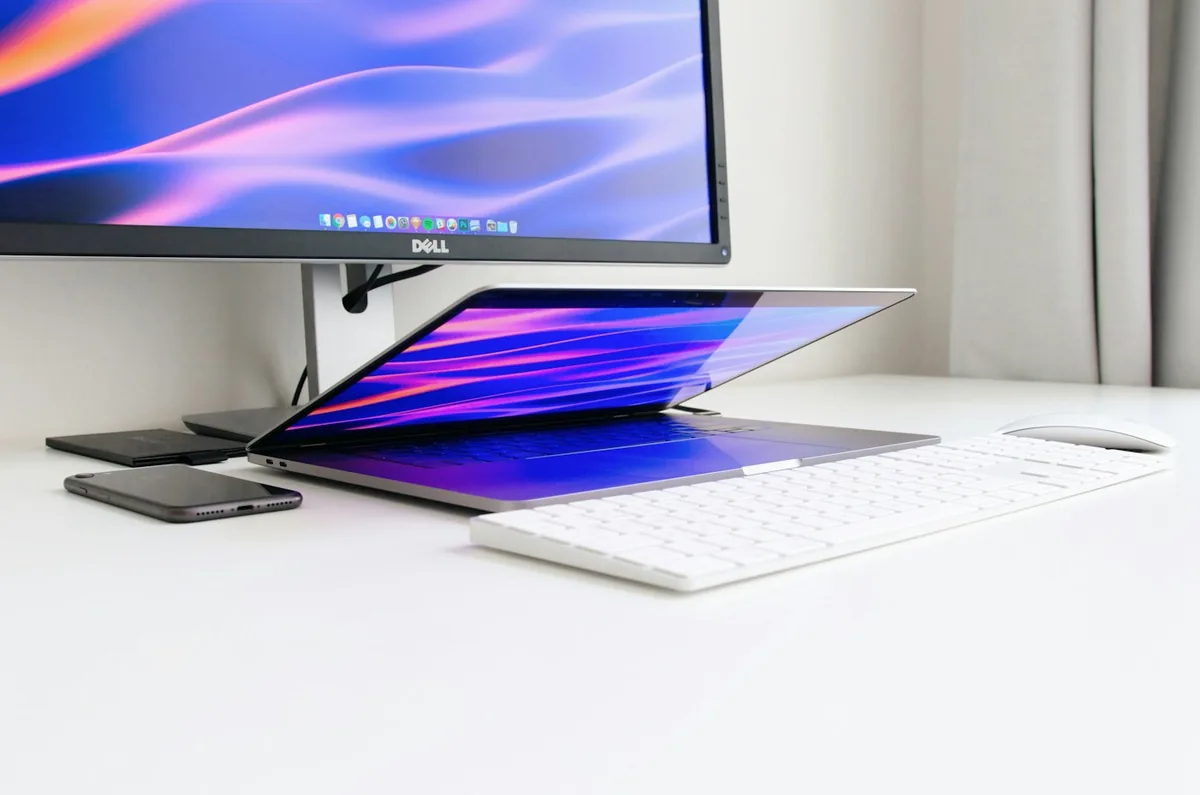 Dell monitor on a white desk in front of a laptop, keyboard and mouse