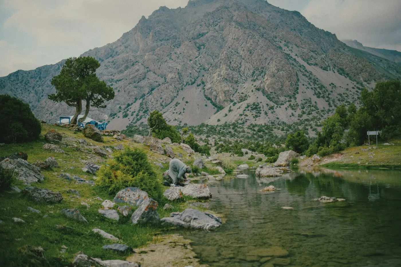 Felsiges Bergtal mit einem grünen See, an dem ein Wanderer Wasser auffüllen könnte