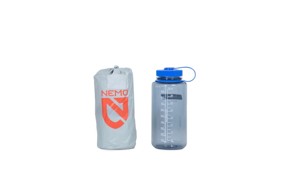 NEMO Tensor All-Season empacada en su bolsa de almacenamiento junto a una botella de agua de un litro para comparar el tamaño