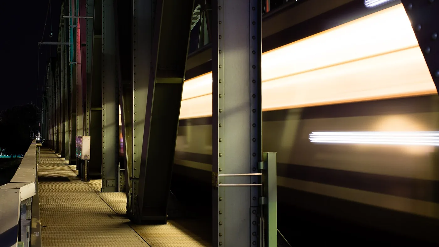 Night train passing a platform under a steel bridge, the long trips an e-reader is made for