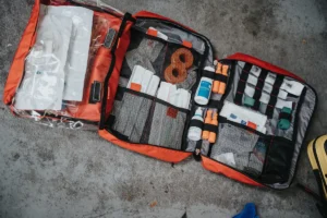 An open red first aid bag with its supplies laid out in mesh pockets
