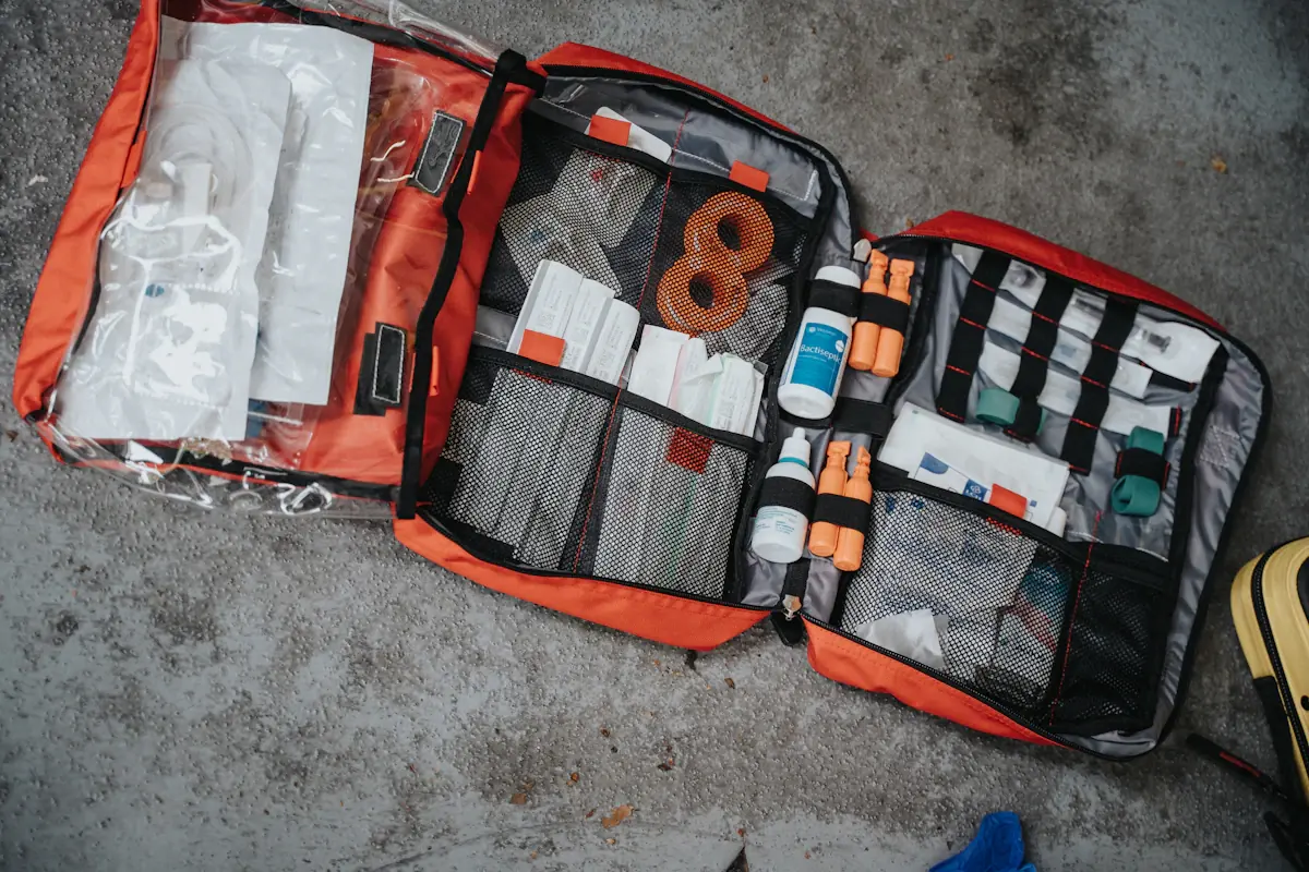 An open red first aid bag with its supplies laid out in mesh pockets