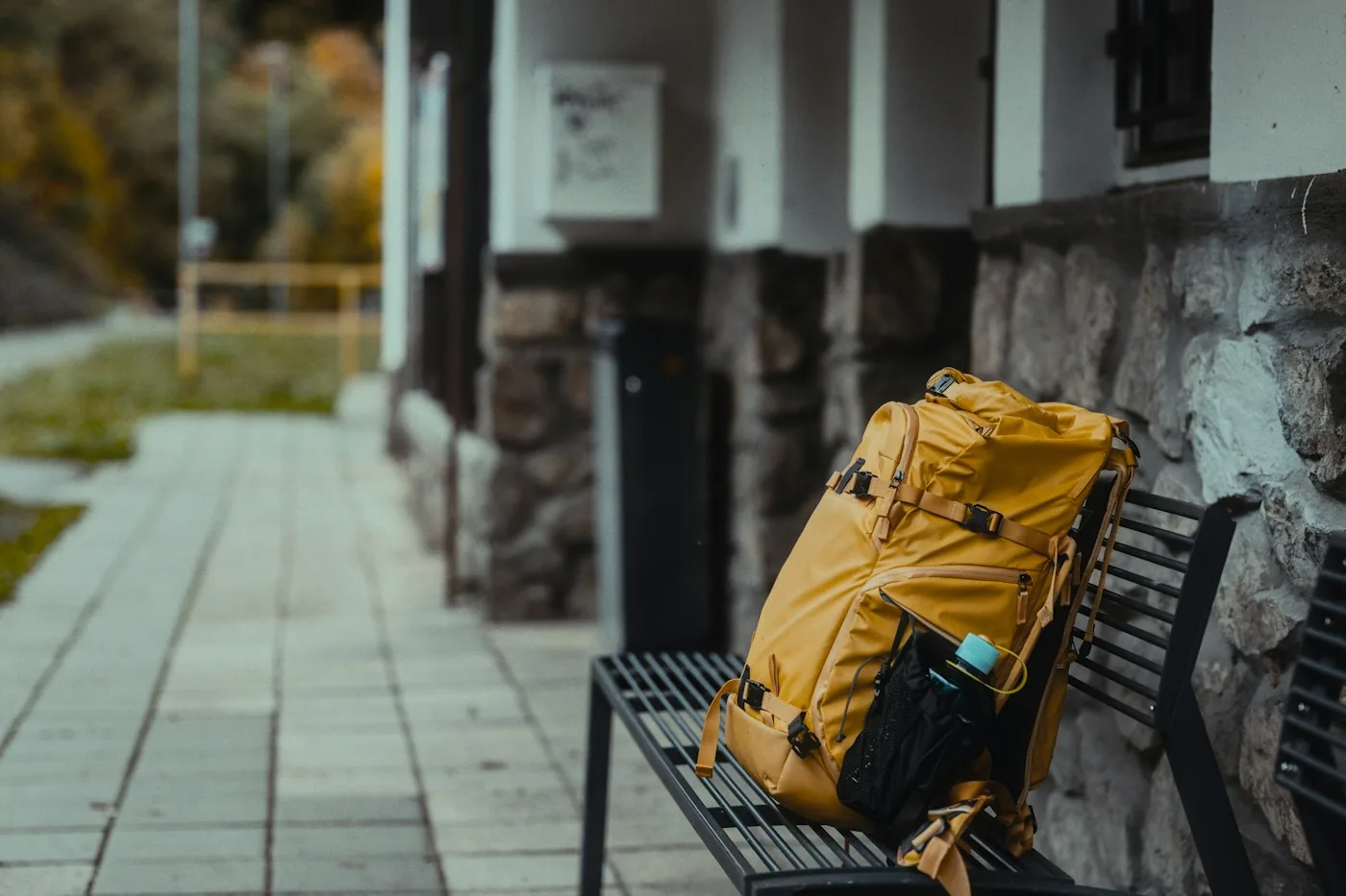 Yellow travel backpack on a bench at a train station platform