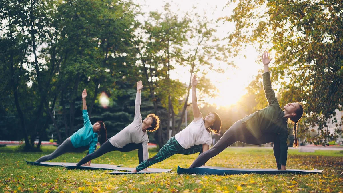 Four people doing a side angle yoga pose on a park lawn at sunset
