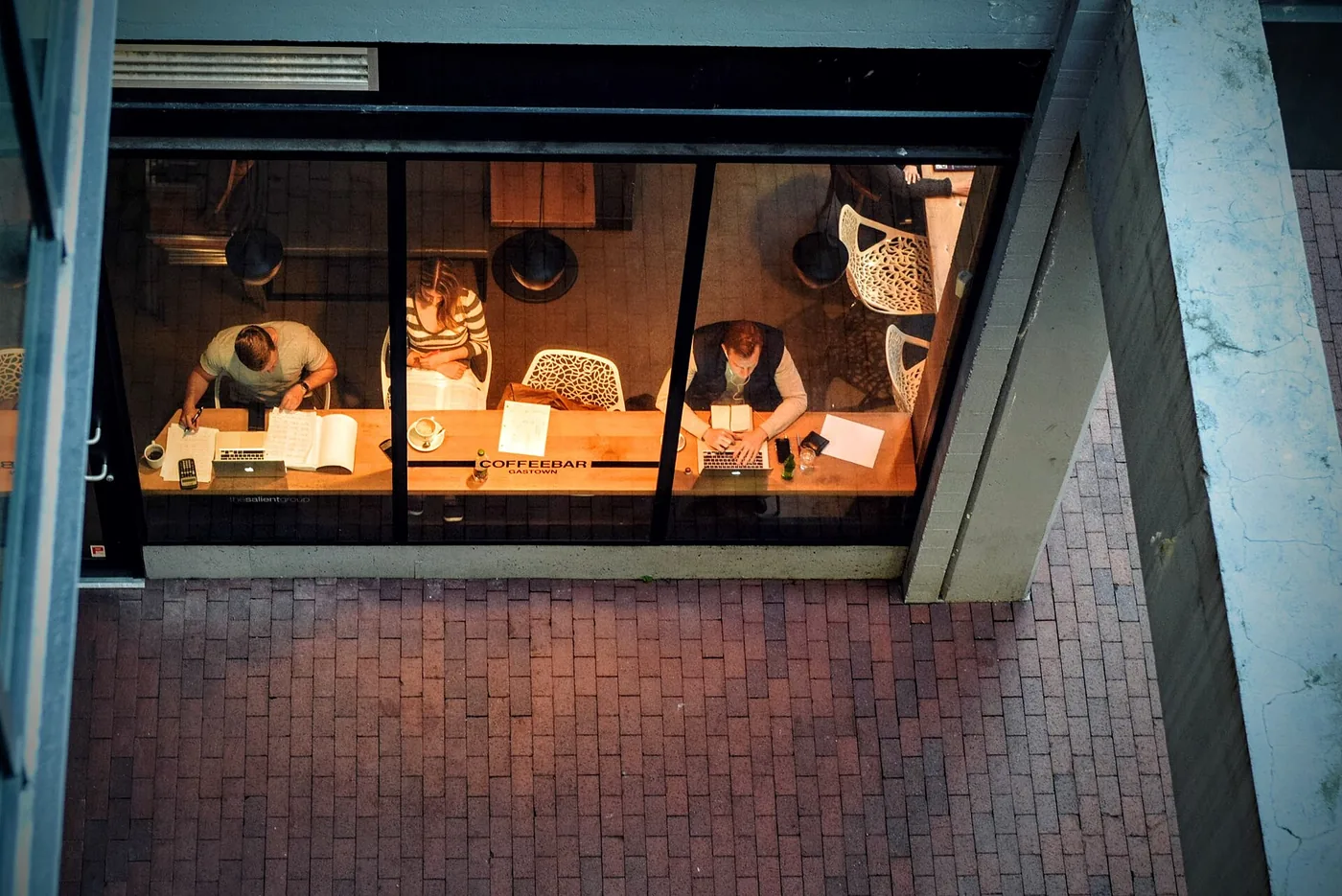 People working at a long table in a coffee shop, seen from above through the window
