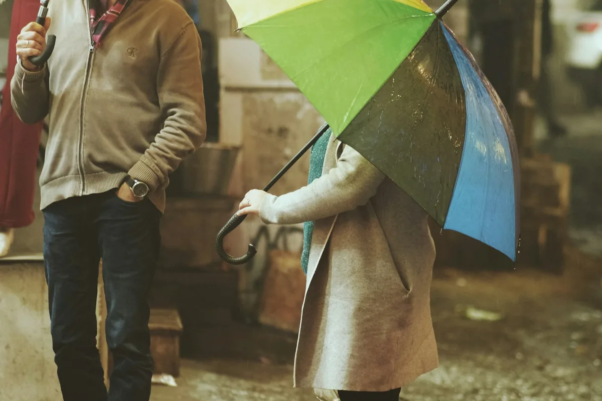 Mensen met gele en groene paraplu's die 's nachts door de regen lopen op straat