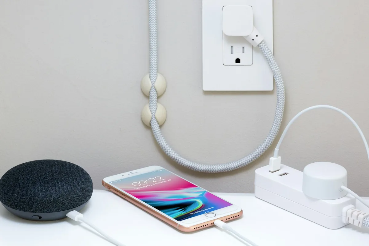 Een telefoon die oplaadt via een kleine wandoplader op een bureau