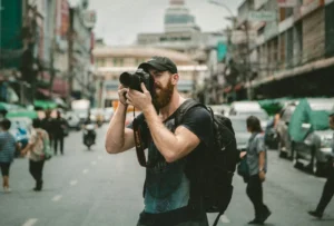 Photographer with a camera and a backpack on a busy street: travel photos to back up