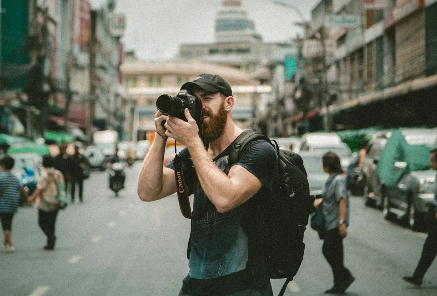 Photographer with a camera and a backpack on a busy street: travel photos to back up