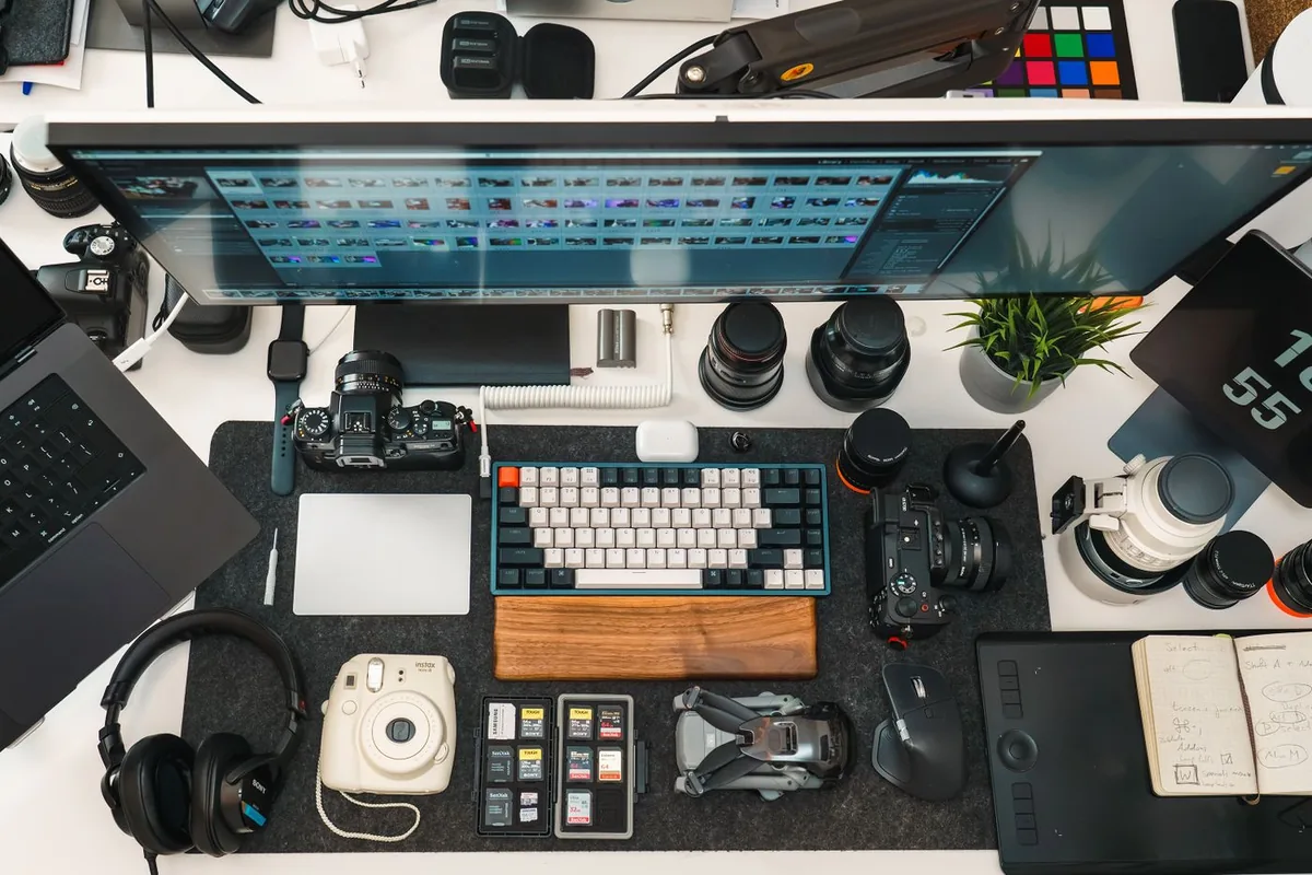 Flat lay of a photographer desk with cameras, a keyboard, headphones and other gear