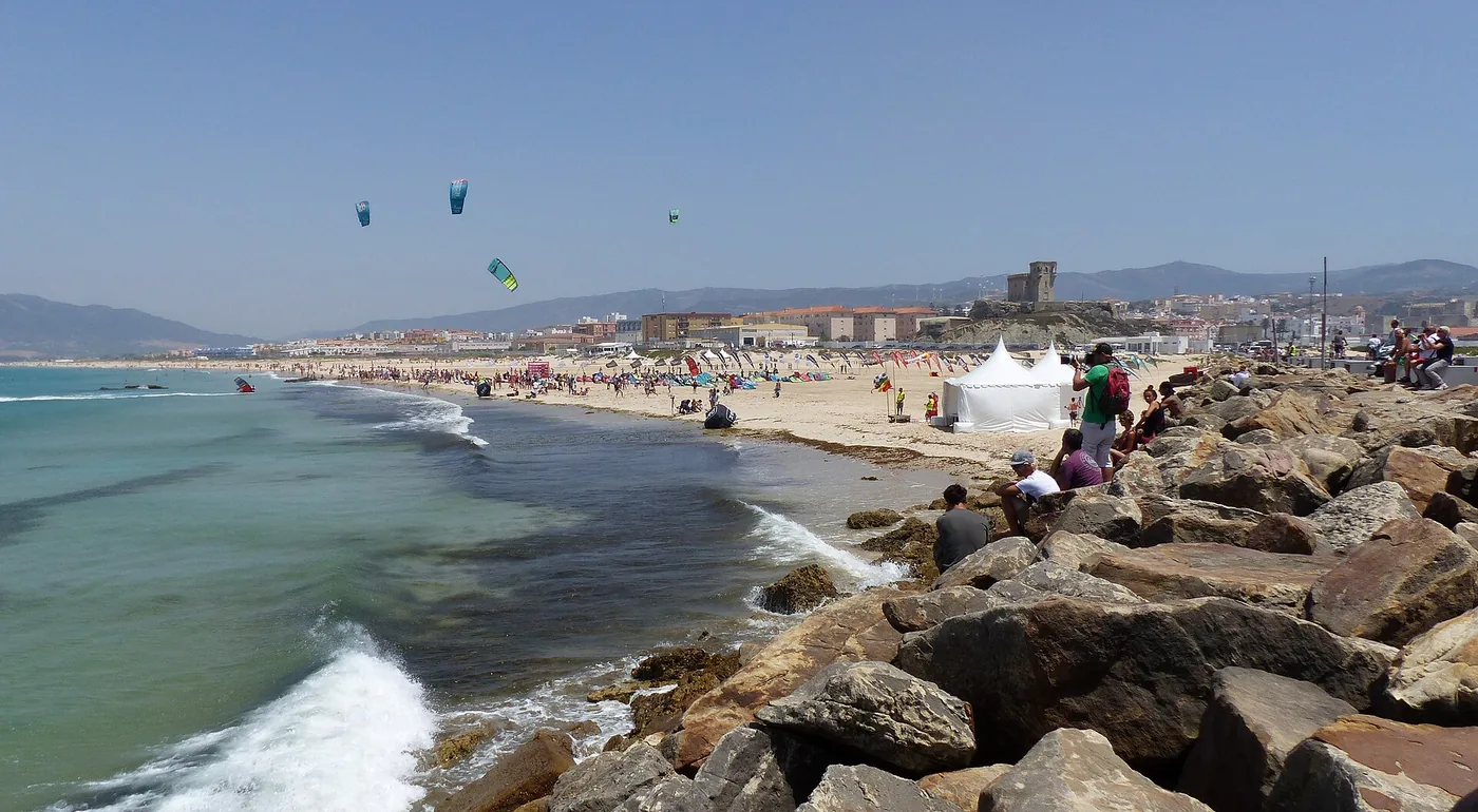 Kites above the water at Playa de Los Lances in Tarifa with rocks in front
