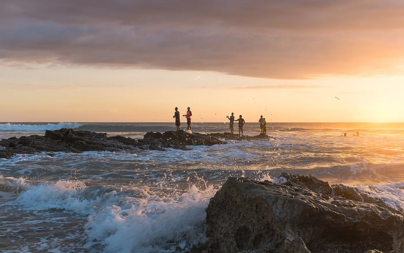 People watching waves from the rocks at sunset on Playa Santa Teresa, Costa Rica