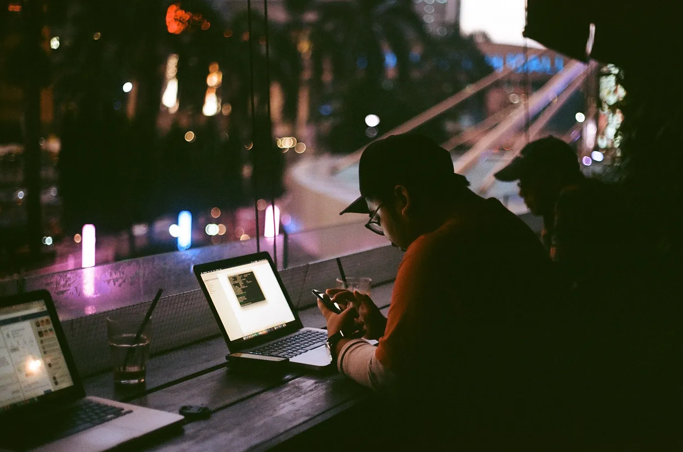 Remote worker typing on a laptop in a dim room, a late work session where a second screen helps