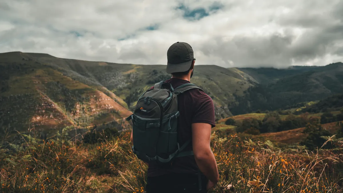 Traveler with a backpack looking over a mountain valley, SafetyWing vs World Nomads travel insurance