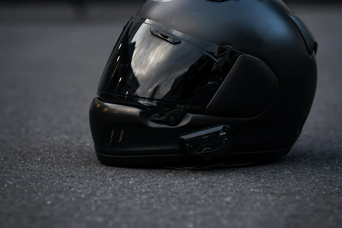 Black motorcycle helmet on the ground next to a motorcycle, scooter helmet rules