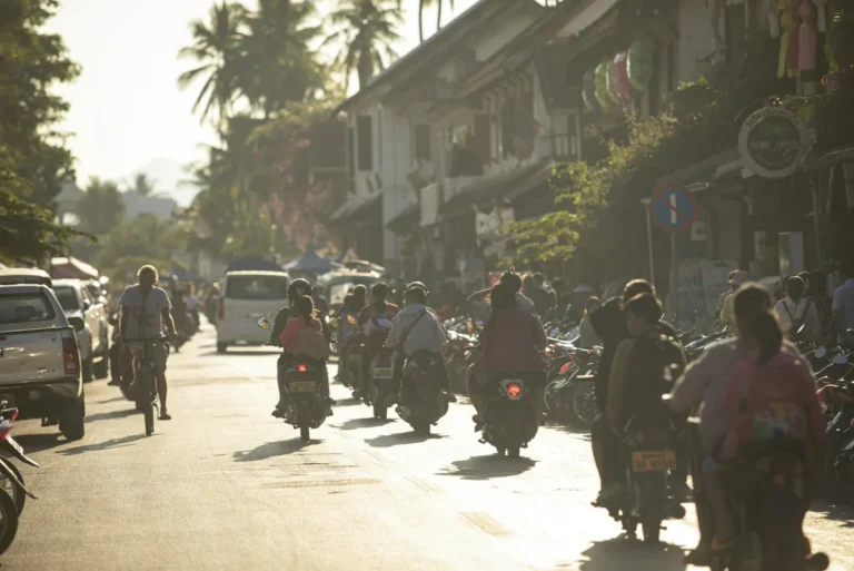 Riders on motorbikes and scooters on a sunlit tropical street, scooter rental in Southeast Asia