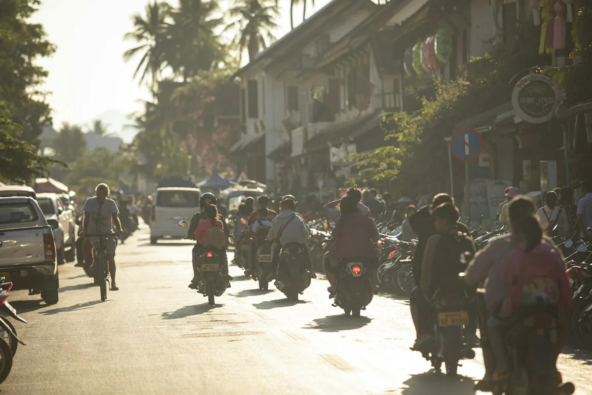 Riders on motorbikes and scooters on a sunlit tropical street, scooter rental in Southeast Asia