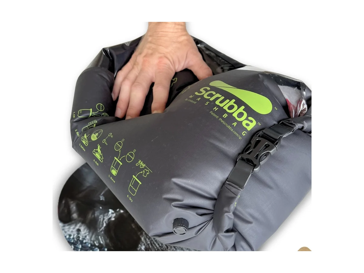 Een hand drukt op de grijze Scrubba wasbag met het wasbord aan de binnenzijde
