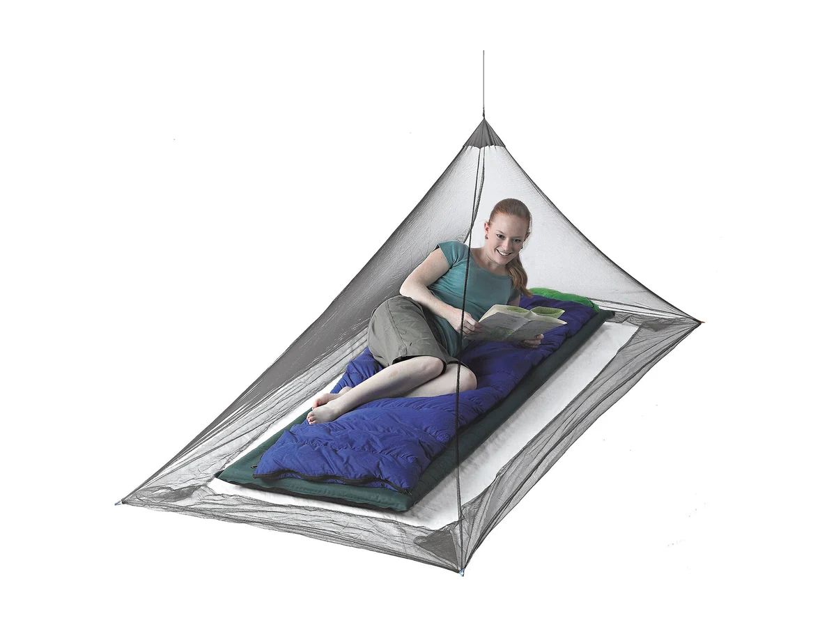 Sea to Summit Mosquito Pyramid Net opgehangen boven een blauwe mat, met een lezende vrouw erin