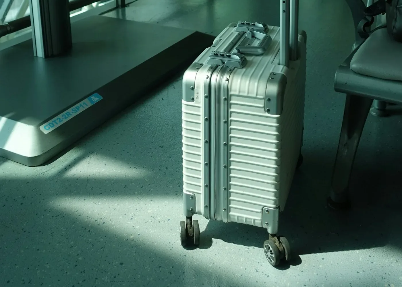Silver ribbed suitcase with its handle extended standing in a bright modern airport corridor