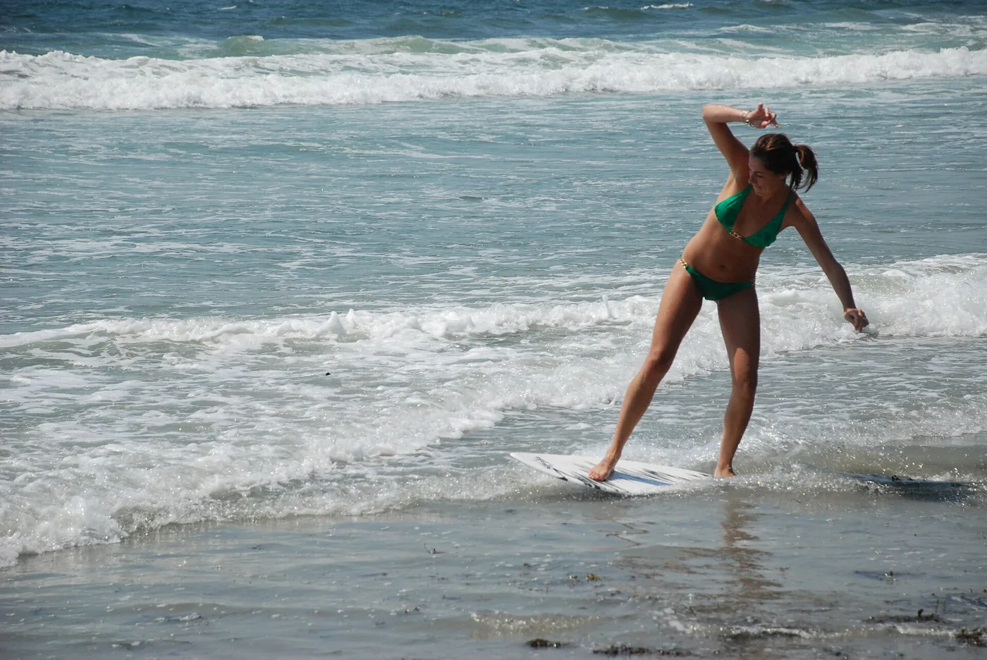 Woman skimboarding on shallow water at Higgins Beach, Maine