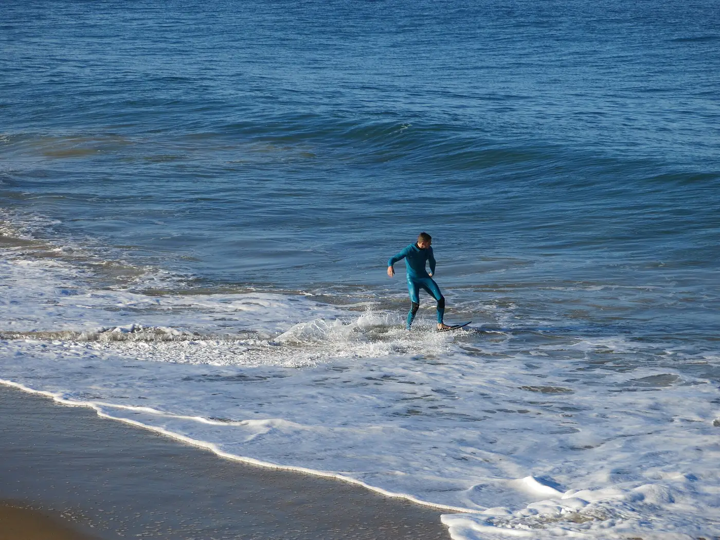 Skimboarder riding a small wave at Capbreton in France