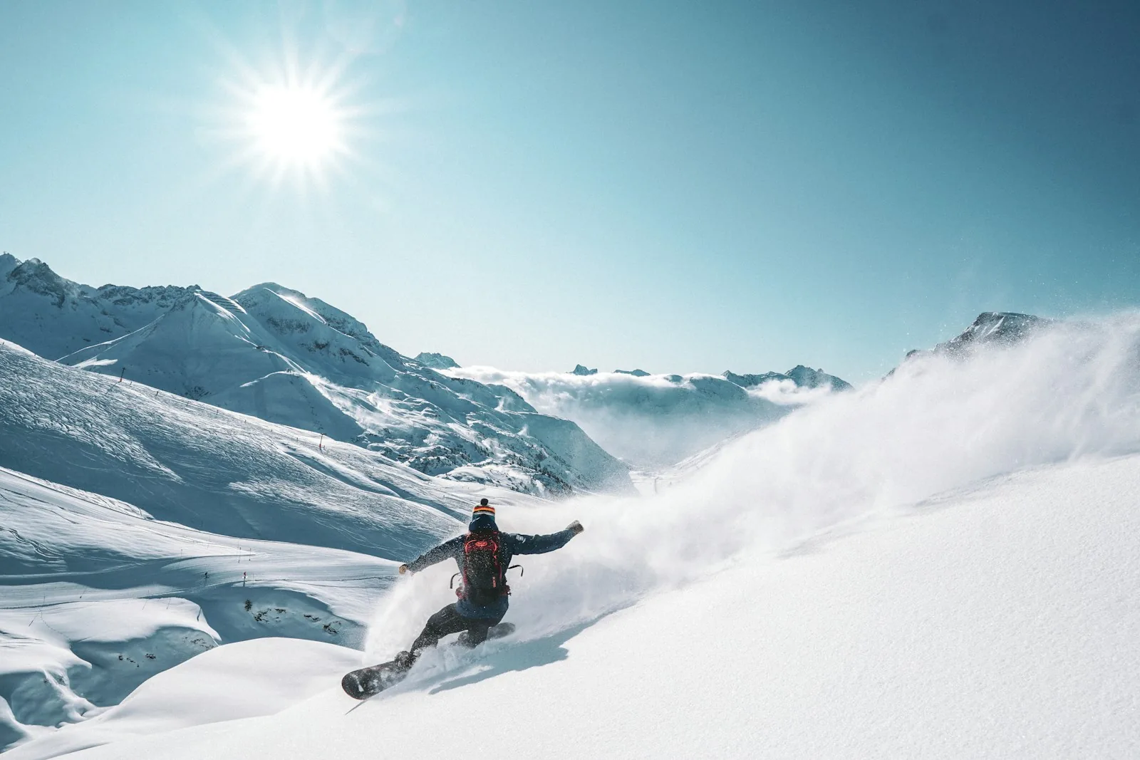A snowboarder carving through fresh powder on a sunny mountain slope