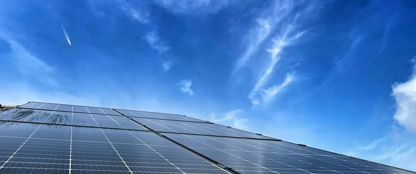 Solar panel tilted toward a blue sky with thin clouds